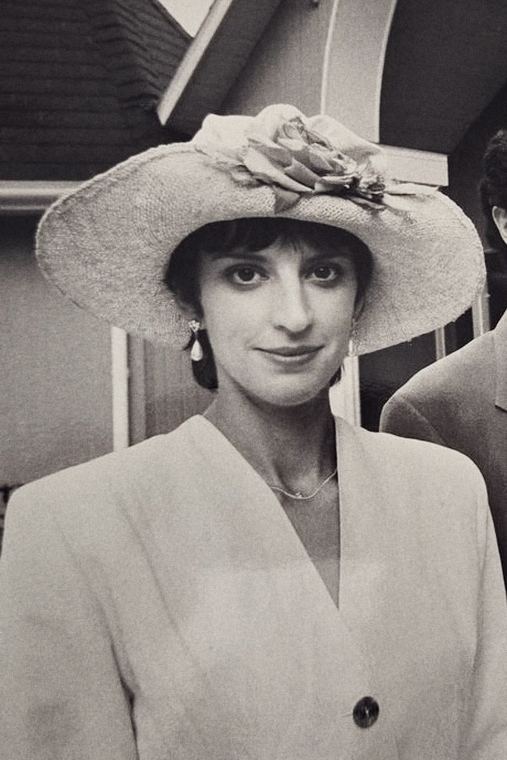 Josée en tailleur clair et large chapeau orné d'une fleur.