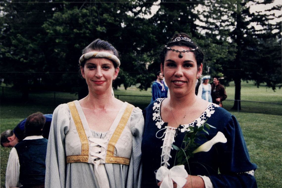Josée en robe médiévale bleue avec un diadème, aux côtés d'une amie en robe pâle.